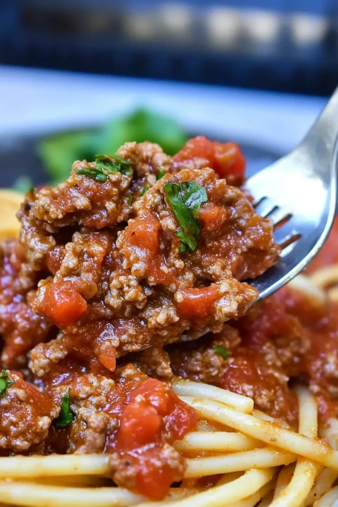 Ground Beef Spaghetti With Rich Sauce – Quick Family Favorite 6 A forkful of spaghetti with rich, chunky meat sauce, garnished with fresh parsley.
